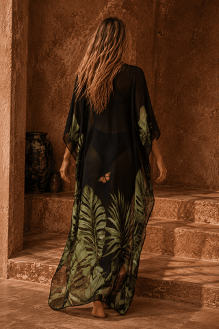 Person wearing a black and green dress with leaf patterns in an indoor setting.