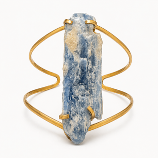 A gold wire wrap cuff bracelet featuring a large, raw blue kyanite crystal cluster as the centerpiece, photographed on a clean white background.