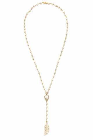 A delicate gold lariat necklace featuring a small heart-shaped bezel with a white inlay, connected to a long drop chain that ends in a polished gold feather pendant, shown against a plain white background.